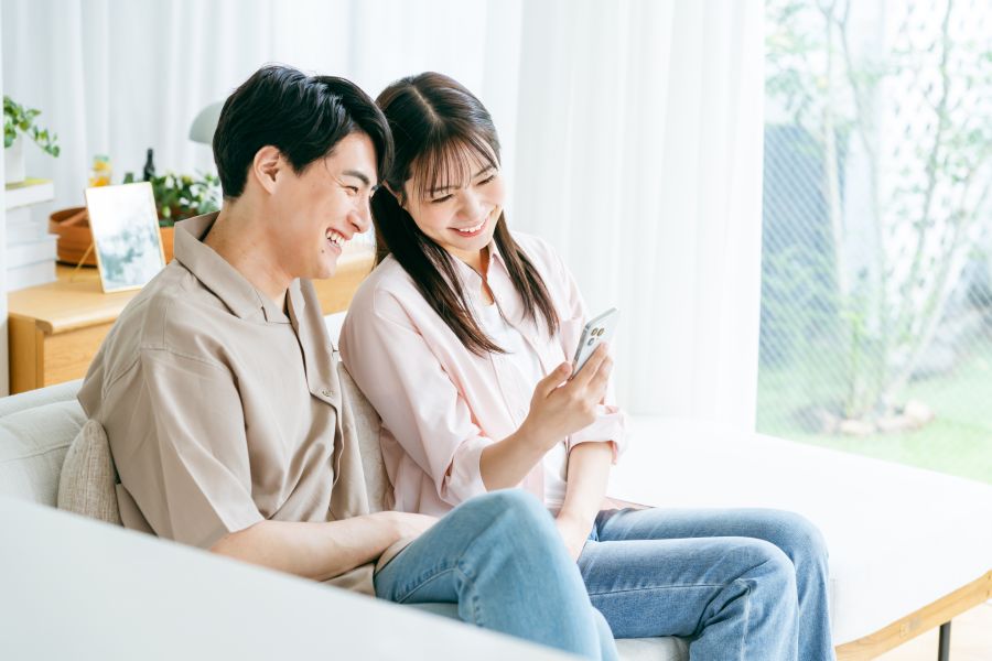ソファに座ってスマホの画面を眺める男女